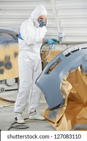 Auto Mechanic Worker Painting Car Bumper At Automobile Repair And Renew Service Station Shop By Spraing Black Color Paint