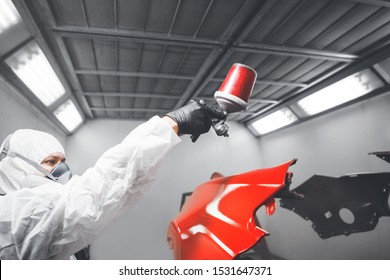 Auto Mechanic Worker Painting Car Element With Spray Gun In A Paint Chamber During Repair Work.