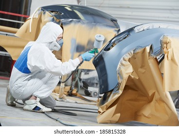 Auto Mechanic Worker Painting Car Bumper At Automobile Repair And Renew Service Station Shop By Spraing Black Color Paint