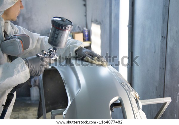 auto mechanic worker painting car in a paint chamber\
during repair work