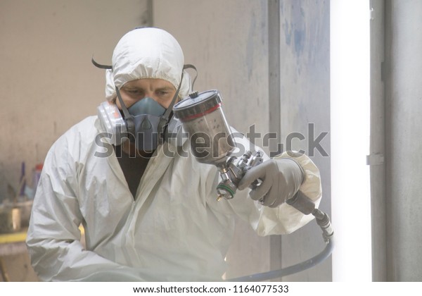 auto mechanic worker painting car in a paint chamber\
during repair work
