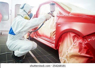 auto mechanic worker painting a red car in a paint chamber during repair work