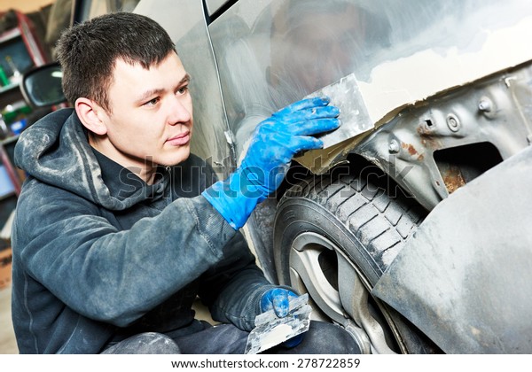 auto\
mechanic worker plastering body car at automobile repair and renew\
service station shop before painting\
restoration