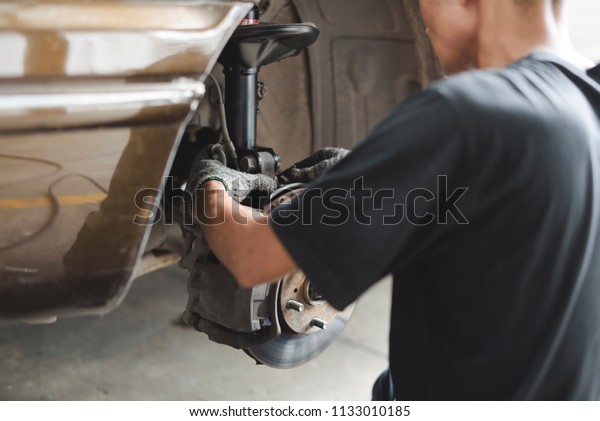 Auto
mechanic worker repairing suspension at
garage.