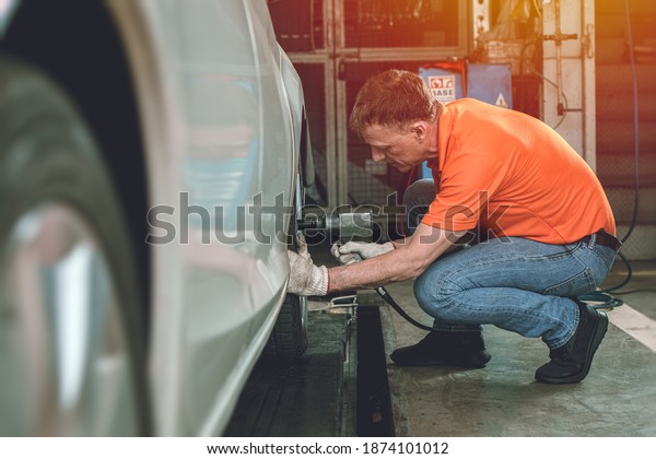 Auto mechanic worker service\
car by checking inflate or change tires in garage automobile\
workshop