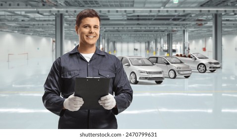 Auto mechanic worker in a uniform holding a clipboard at a car manufacturing workshop - Powered by Shutterstock