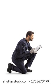 Auto mechanic worker in a uniform kneeling and writing a document isolated on white background