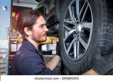 Auto Mechanic Working In Garage, Checking Wheels, Car Service Technician Repairing Customer Car At Automobile Service Center, Inspecting Car Under Body And Suspension System, Vehicle Repair Shop.