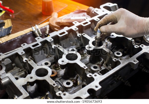 Auto mechanic working in garage. Repair\
service.  opened automobile engine cylinder head for maintenance\
repair at car service station for\
diagnosis