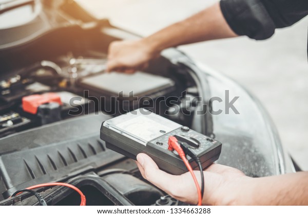 Auto mechanic working in garage Technician Hands\
of car mechanic working in auto repair Service and Maintenance\
check car battery.