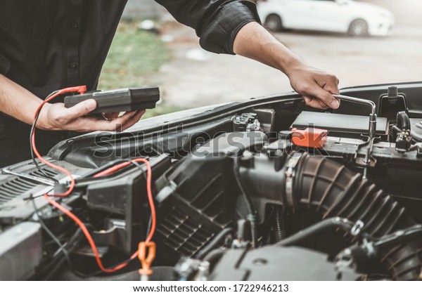 Auto mechanic working in garage Technician Hands\
of car mechanic working in auto repair Service and Maintenance car\
battery check.