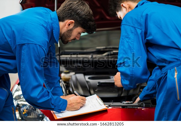Auto mechanic working in
garage.Vehicle service maintenance young handsome men check car
condition in garage. Auto Service Center, repair, maintenance
concept 