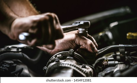 Auto mechanic working on car engine in mechanics garage. Repair service. authentic close-up shot - Powered by Shutterstock