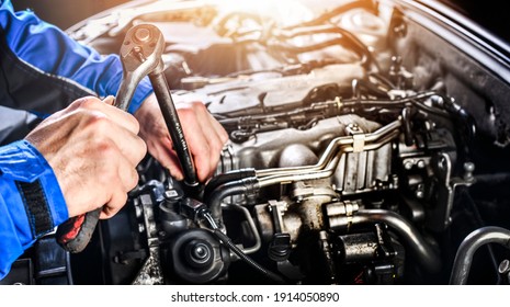 Auto mechanic working on car broken engine in mechanics service or garage. Transport maintenance wrench detial.