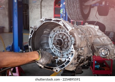 Auto mechanic working on car automatic transmission in auto repair shop.