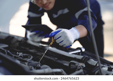 Auto mechanic is working on car engine in mechanic shop. A mechanic in uniform is working on a car service. Work in repair shops and maintenance services. - Powered by Shutterstock