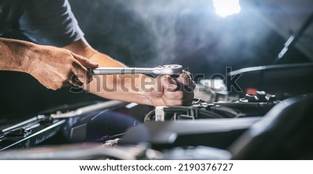 Auto mechanic working on car engine in mechanics garage. Repair service. authentic close-up shot - selective focus with motion blur
