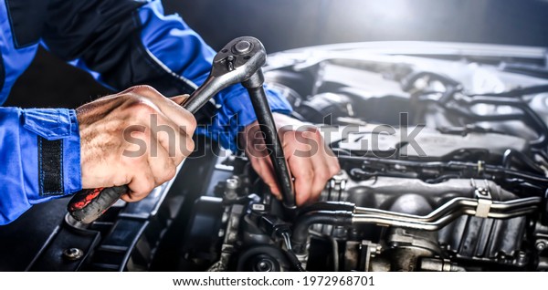 Auto
mechanic working on car broken engine in mechanics service or
garage. Transport maintenance wrench
detial.