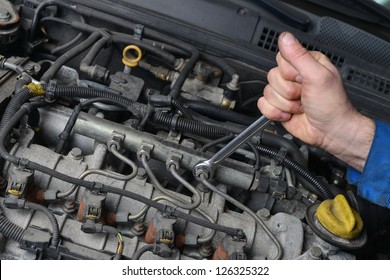 Auto Mechanic is working on engine in car repair shop.