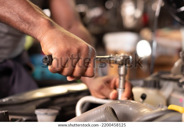 Auto mechanic working and\
repair on car engine in mechanics garage. Car service. male\
mechanic repairs car in garage. Car maintenance and auto service\
garage concept.
