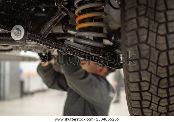 An auto mechanic working in a service station.\
Service of cars