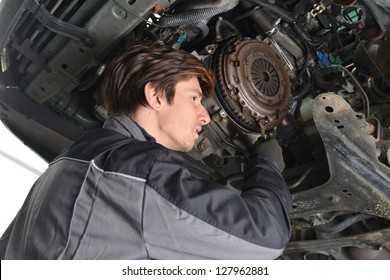   Auto Mechanic Working Under The Car And Changing Clutch At Car Repair Shop