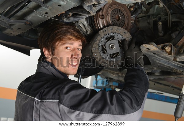   Auto mechanic working under the car and\
changing clutch at car repair\
shop
