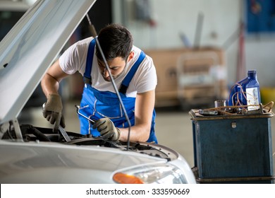 Auto Mechanic Working Under The Hood In Garage