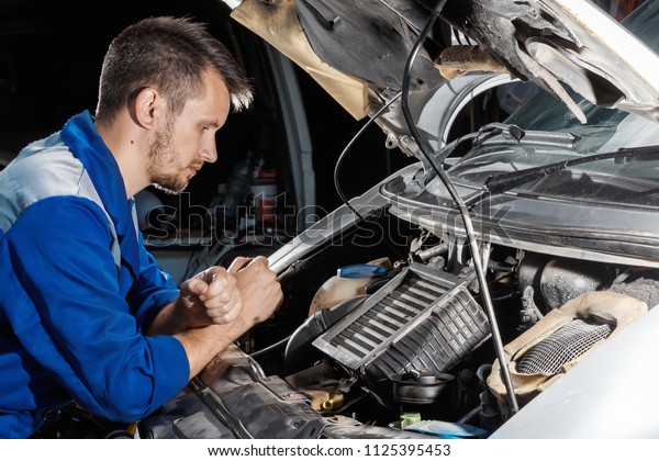 The auto mechanic works in the\
garage. Repair service. Maintenance of the car, car\
repair.
