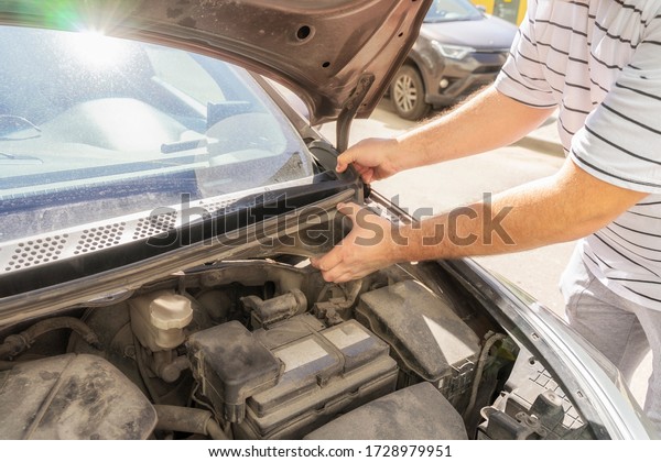 Auto mechanic works in the\
garage. Repairs. Removing the plastic panel to repair the\
trapezoid