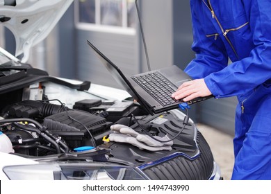 
An Auto Mechanic Works With A Laptop On A Car