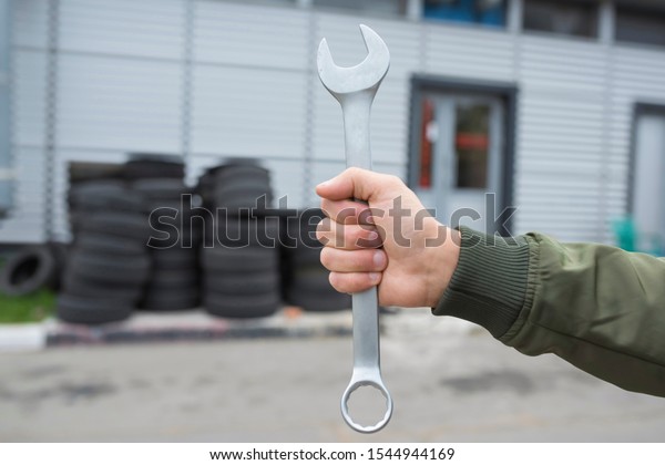 Auto mechanic wrench\
in hand, on the background of the garage. Automobile repair service\
concept.