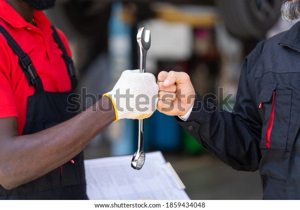 Auto mechanic
with wrench in hand. stranglehold. Closeup car repair black man
hand and caucasian man customer.
