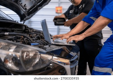 Auto mechanics analyzing car engine data with a laptop in a repair shop
