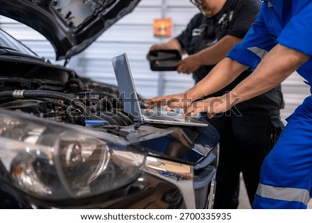 Auto mechanics analyzing car engine data with a laptop in a repair shop