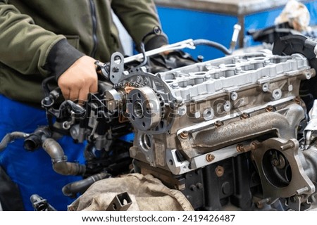 Auto mechanics assembling a disassembled car engine in a workshop