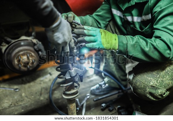 Auto mechanics compress\
the spring with zip ties to replace the shock absorber. Car\
suspension repair.