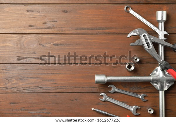Auto mechanic\'s tools on wooden background, flat\
lay. Space for text