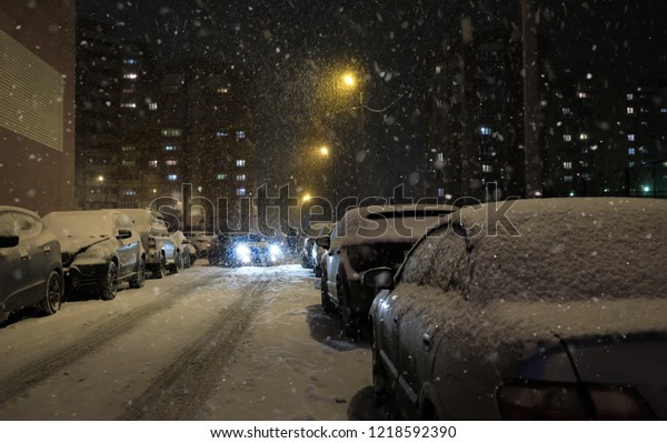 Auto parked in bad snowy weather. winter\
season in city. Cars under snow at night time.\
