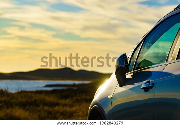 Auto parking on seashore in sunset\
time. Rear view mirror closed for safety at car\
park.