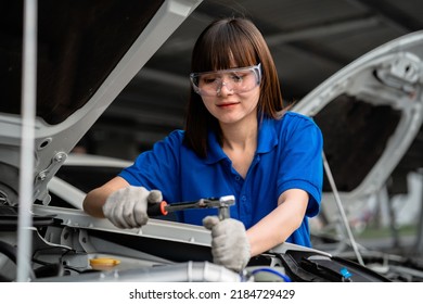 Auto Repair Concept. An Asian Female Handyman Wearing A Blue Shirt In A Garage. Happy Female Mechanic In The Auto Repair Service Center. Mechanic Inspector Of A Car Or Vehicle