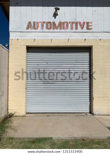Auto repair garage with door and Automotive sign\
painted on the building