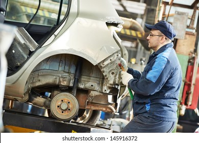 auto repair man worker flatten and align metal body car with hammer in automotive industry