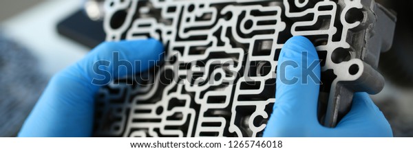The auto repair service repairman in automatic
gearboxes holds in his hand in blue protective gloves the
hydroblock detail dehydrates the diagnostics and estimates detail
test transmission closeup.