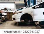 An auto repair shop with mechanics repairing cars using specialized tools and hydraulic lifts. The industrial work area is filled with equipment for engine repair.