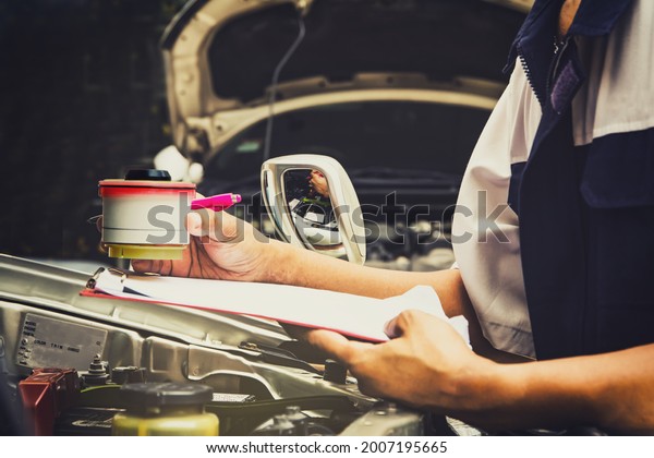 Auto repair work in the garage : Mechanic\
replaces the genuine diesel fuel filter on a pickup truck to\
replace a new one by guaranteeing repair work and recording the\
repair history on the\
clipboard.