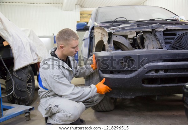 Auto repairman
plastering autobody bonnet. Auto mechanic worker painting car in a
paint chamber during repair
work.