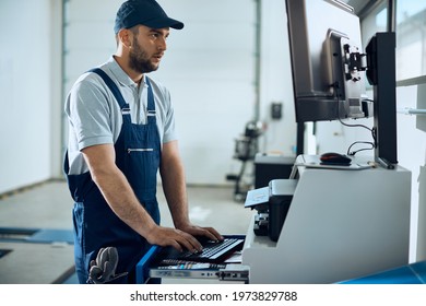 Auto Repairman Using Computer While Working At Car Workshop. 