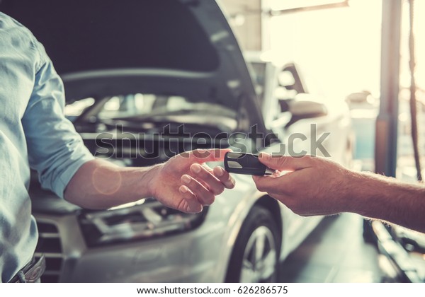 At the auto service. Cropped image of auto\
mechanic returning car key to a\
client
