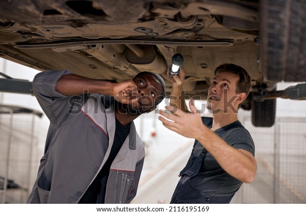 Auto
service with mechanical team for check suspension of SUV car using
Lamp, Black And Caucasian Auto mechanics repair car,service via
insurance system at modern clean garage, team
work